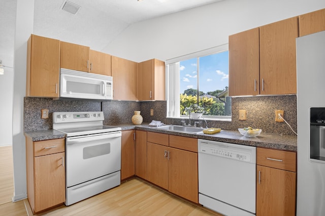 2915 NW 14th St, Delray Beach, FL 33445 - kitchen featuring white appliances, light wood finished floors, dark countertops, decorative backsplash, and lofted ceiling