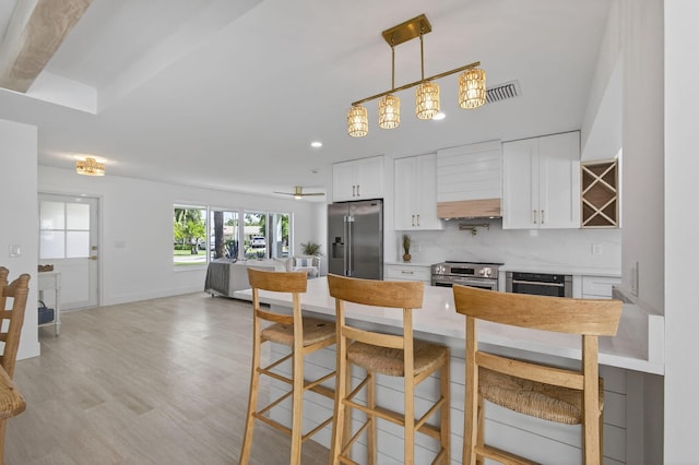 131 Cruiser Rd S, North Palm Beach, FL 33408 - kitchen featuring stainless steel appliances, custom exhaust hood, a breakfast bar area, white cabinetry, and open floor plan