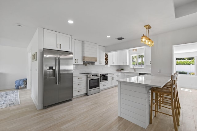 131 Cruiser Rd S, North Palm Beach, FL 33408 - kitchen featuring appliances with stainless steel finishes, a peninsula, plenty of natural light, white cabinetry, and recessed lighting