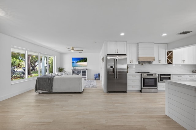131 Cruiser Rd S, North Palm Beach, FL 33408 - kitchen featuring appliances with stainless steel finishes, light countertops, white cabinets, light wood-style floors, and premium range hood