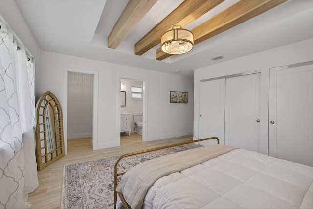131 Cruiser Rd S, North Palm Beach, FL 33408 - bedroom with light wood finished floors, beam ceiling, ensuite bath, and two closets