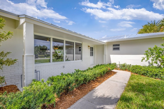 131 Cruiser Rd S, North Palm Beach, FL 33408 - view of exterior entry featuring brick siding, stucco siding, and a metal roof