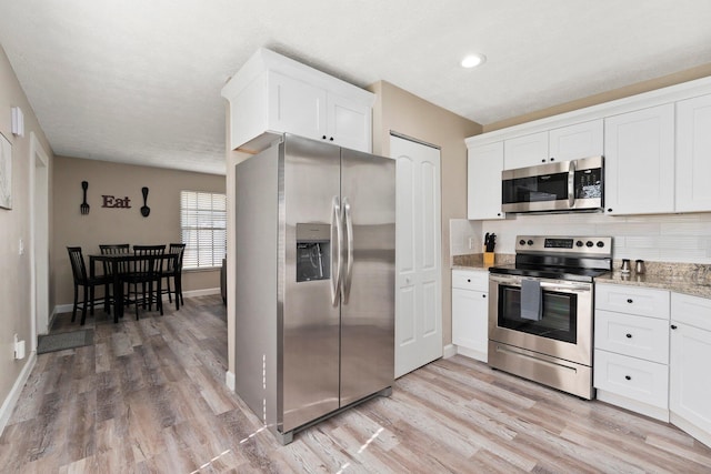 1251 SW Sudder Ave, Port Saint Lucie, FL 34953 - kitchen featuring appliances with stainless steel finishes, light wood-type flooring, tasteful backsplash, and white cabinets