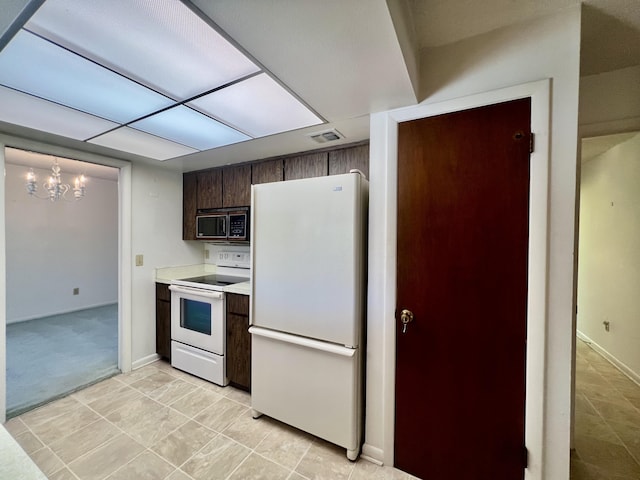 115 15th Ave, Vero Beach, FL 32962 - kitchen with white appliances, dark brown cabinetry, a chandelier, and light countertops