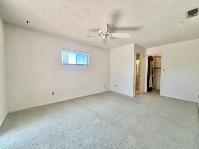 115 15th Ave, Vero Beach, FL 32962 - unfurnished bedroom featuring light carpet, a textured ceiling, a ceiling fan, a spacious closet, and a closet