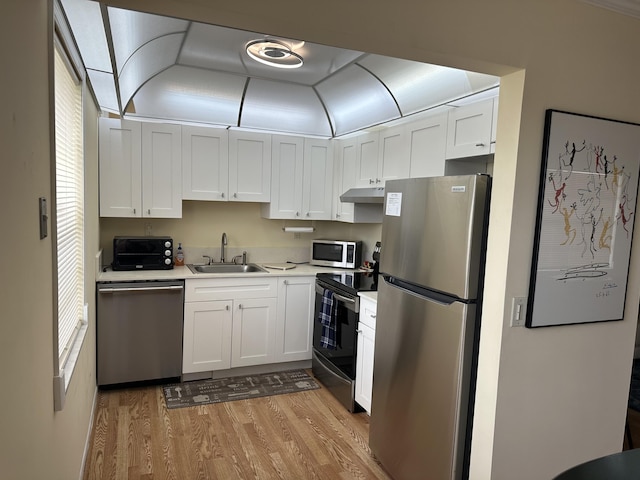 313 Normandy Unit G, Delray Beach, FL 33484 - kitchen featuring appliances with stainless steel finishes, under cabinet range hood, light wood-type flooring, white cabinets, and light countertops