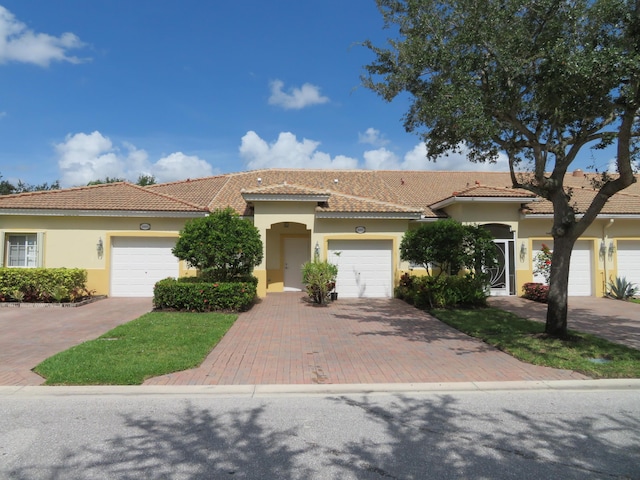 2357 Windjammer Way, West Palm Beach, FL 33411 - view of front of house featuring stucco siding, decorative driveway, a tile roof, and an attached garage