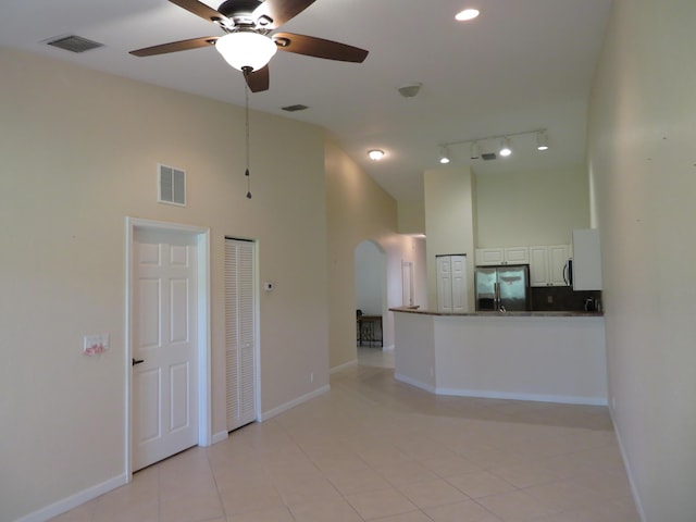 2357 Windjammer Way, West Palm Beach, FL 33411 - unfurnished living room with a towering ceiling, arched walkways, a ceiling fan, light tile patterned floors, and rail lighting