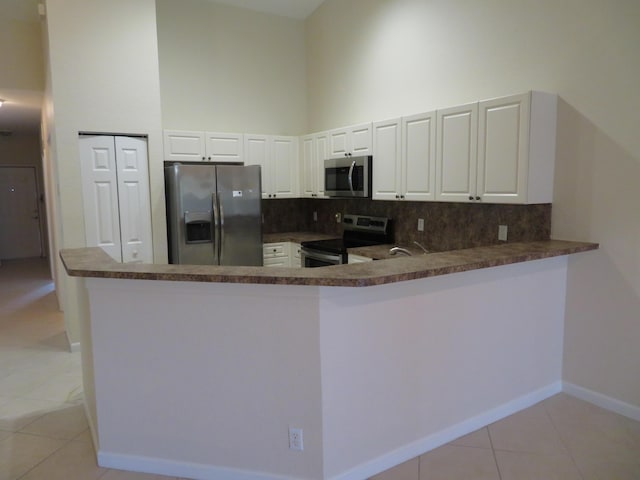 2357 Windjammer Way, West Palm Beach, FL 33411 - kitchen with stainless steel appliances, a high ceiling, backsplash, dark countertops, and light tile patterned floors