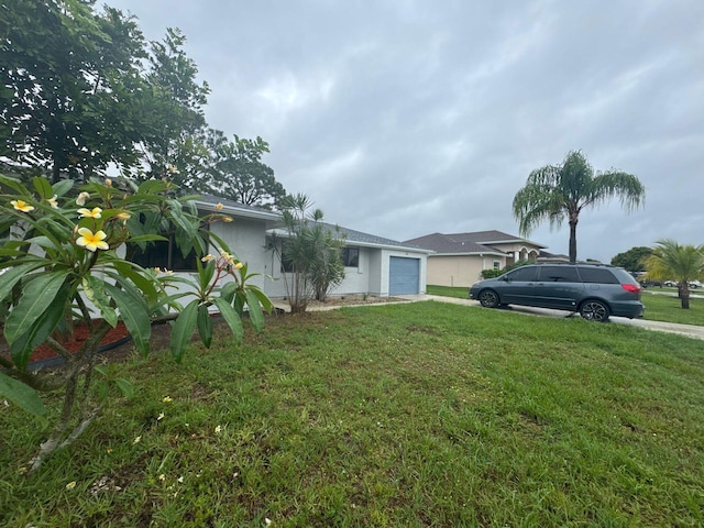 1942 SE Camilo St, Port Saint Lucie, FL 34952 - view of front of house featuring a garage, driveway, a front yard, and stucco siding