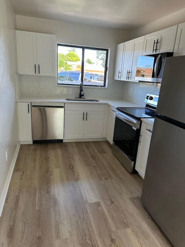 1942 SE Camilo St, Port Saint Lucie, FL 34952 - kitchen featuring appliances with stainless steel finishes, white cabinets, light wood-type flooring, and decorative backsplash