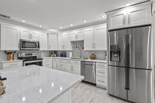 1951 SE Erwin Rd, Port Saint Lucie, FL 34952 - kitchen with stainless steel appliances, white cabinetry, recessed lighting, light stone countertops, and decorative backsplash