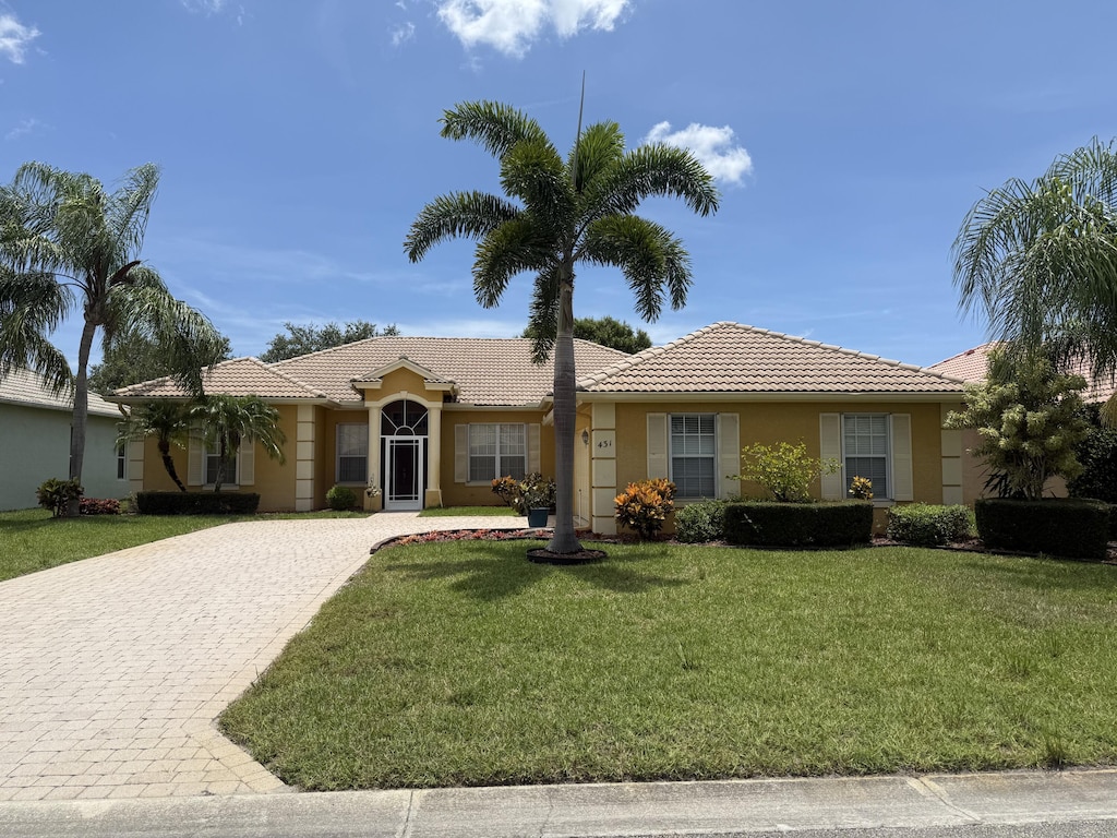 431 NW Canterbury Ct, Port Saint Lucie, FL 34983 - ranch-style house featuring decorative driveway, a tiled roof, a front yard, and stucco siding