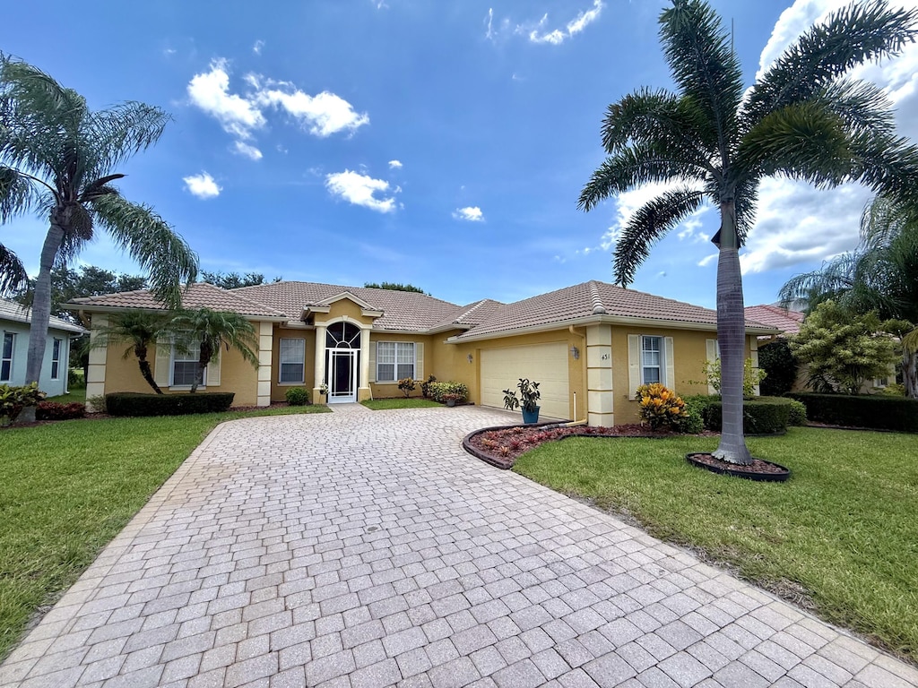 431 NW Canterbury Ct, Port Saint Lucie, FL 34983 - ranch-style home with stucco siding, decorative driveway, a garage, and a front lawn