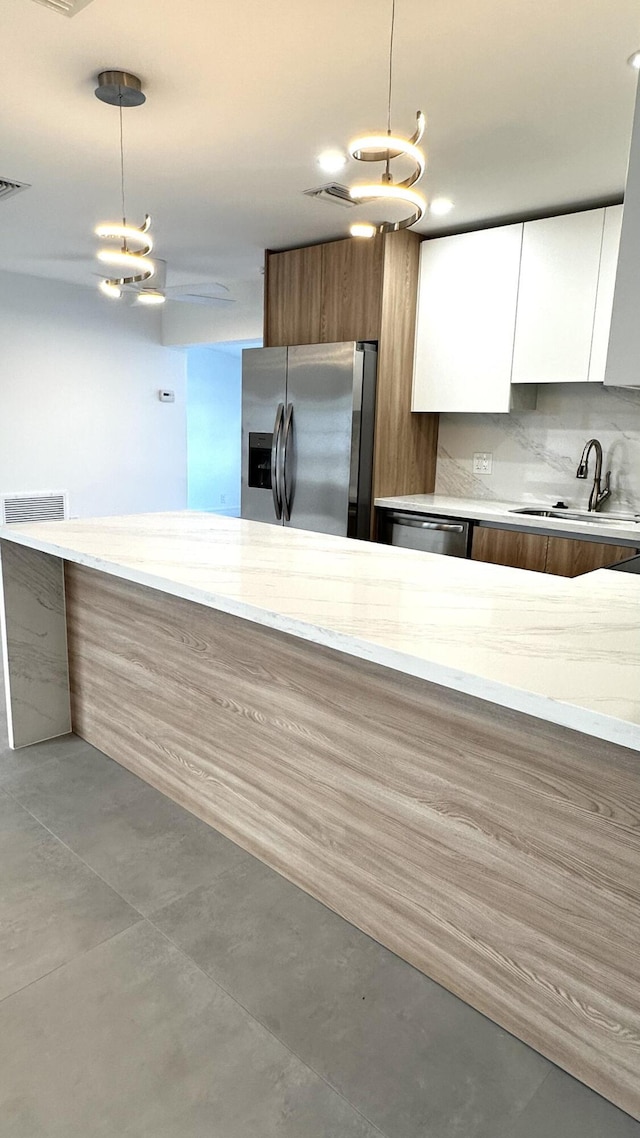 790 Sarazen Dr, West Palm Beach, FL 33413 - kitchen featuring appliances with stainless steel finishes, modern cabinets, white cabinets, light stone countertops, and decorative light fixtures