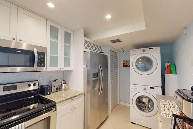 3492 NE Causeway Blvd Unit 104, Jensen Beach, FL 34957 - laundry room featuring estacked washer and dryer, light tile patterned floors, and recessed lighting