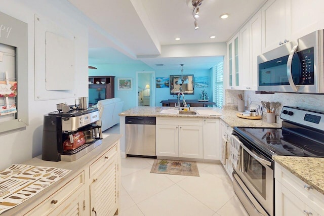 3492 NE Causeway Blvd Unit 104, Jensen Beach, FL 34957 - kitchen with stainless steel appliances, light tile patterned flooring, glass insert cabinets, a peninsula, and white cabinets