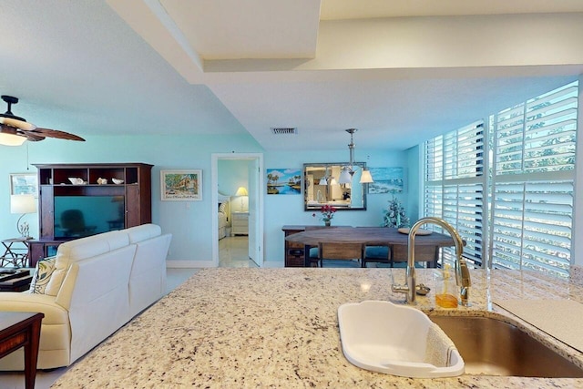 3492 NE Causeway Blvd Unit 104, Jensen Beach, FL 34957 - kitchen featuring a ceiling fan, light stone counters, hanging light fixtures, and open floor plan
