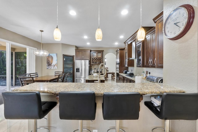 12358 Saint Simon Dr, Boca Raton, FL 33428 - kitchen with stainless steel fridge with ice dispenser, a peninsula, backsplash, a breakfast bar area, and recessed lighting