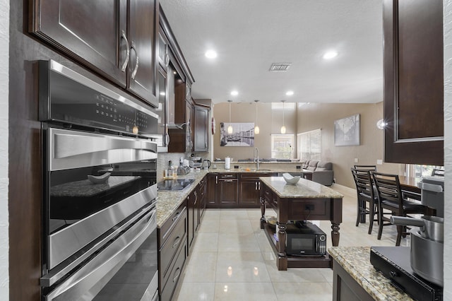 12358 Saint Simon Dr, Boca Raton, FL 33428 - kitchen with black appliances, dark brown cabinetry, light stone countertops, open floor plan, and recessed lighting
