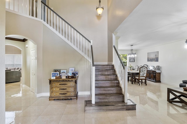 12358 Saint Simon Dr, Boca Raton, FL 33428 - stairway with arched walkways, tile patterned flooring, a chandelier, and a towering ceiling
