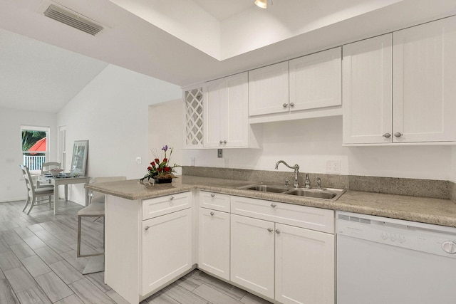 3824 SE Fairway E, Stuart, FL 34997 - kitchen with white dishwasher, a peninsula, white cabinetry, a kitchen bar, and lofted ceiling