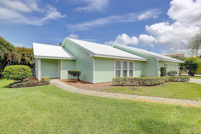 3824 SE Fairway E, Stuart, FL 34997 - view of property exterior with a lawn, a garage, and a metal roof