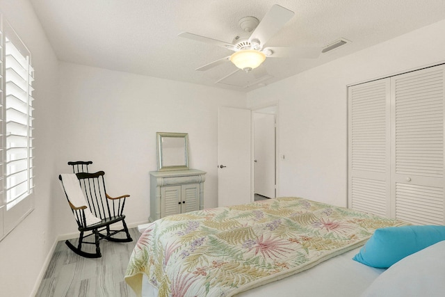 3824 SE Fairway E, Stuart, FL 34997 - bedroom featuring a closet, multiple windows, a ceiling fan, wood finished floors, and a textured ceiling