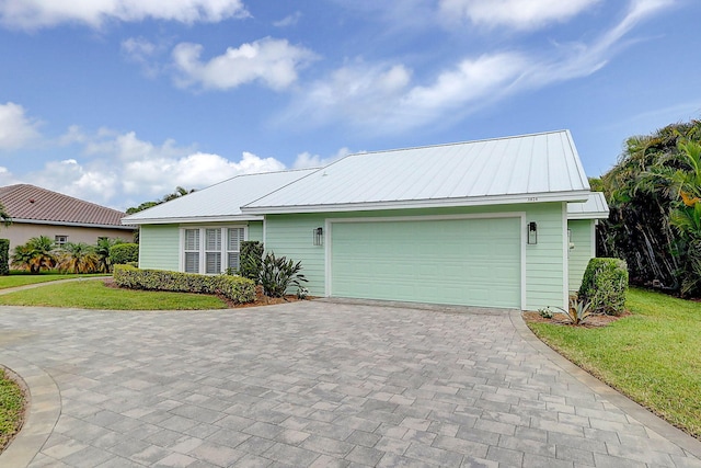 3824 SE Fairway E, Stuart, FL 34997 - view of front of home with a front yard, a metal roof, an attached garage, and decorative driveway