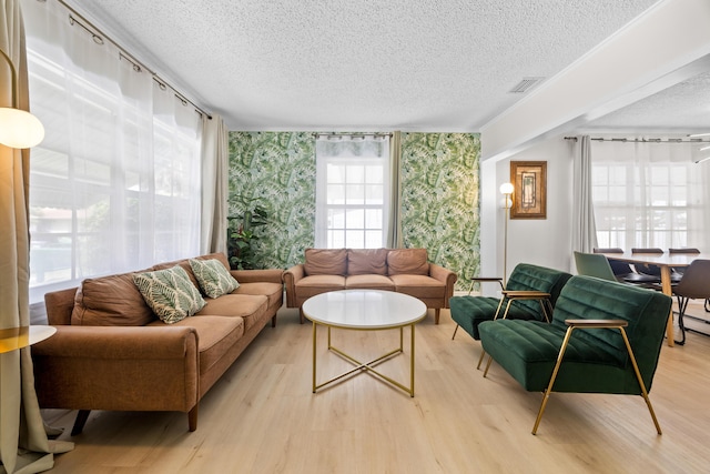 815 Green St, West Palm Beach, FL 33405 - living area featuring wallpapered walls, a textured ceiling, wood finished floors, and an accent wall