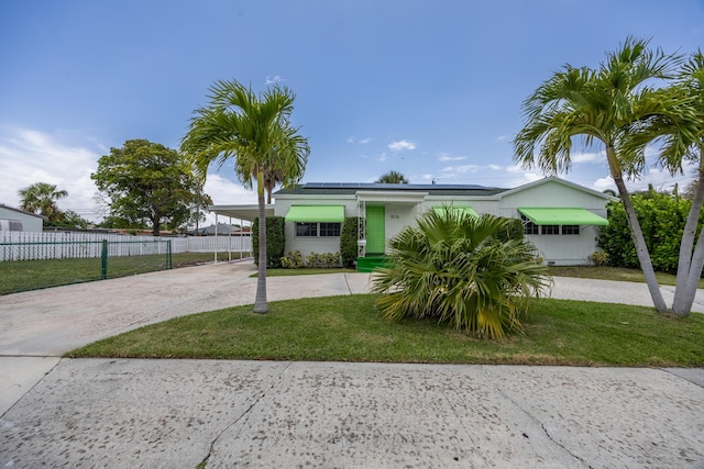 815 Green St, West Palm Beach, FL 33405 - ranch-style house featuring concrete driveway, an attached carport, and roof mounted solar panels