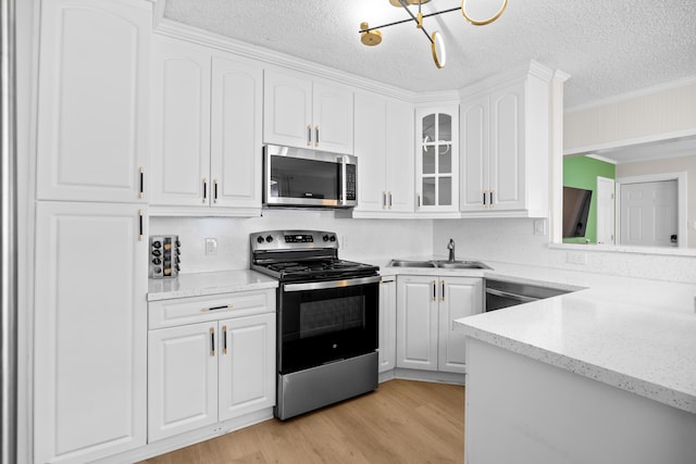 815 Green St, West Palm Beach, FL 33405 - kitchen featuring appliances with stainless steel finishes, a textured ceiling, light wood-style flooring, glass insert cabinets, and white cabinetry