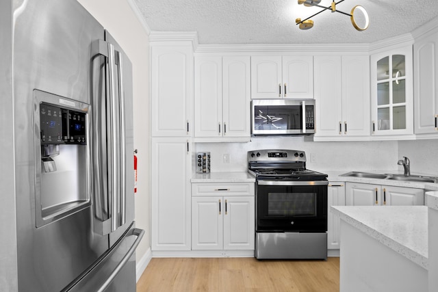 815 Green St, West Palm Beach, FL 33405 - kitchen featuring stainless steel appliances, light wood-style flooring, white cabinetry, glass insert cabinets, and a textured ceiling