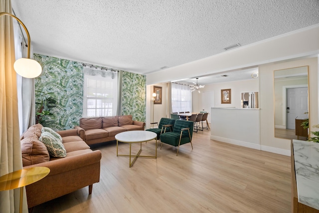 815 Green St, West Palm Beach, FL 33405 - living room with a textured ceiling, light wood-style flooring, a chandelier, and wallpapered walls