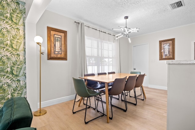 815 Green St, West Palm Beach, FL 33405 - dining area featuring light wood finished floors, a chandelier, a textured ceiling, and ornamental molding