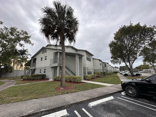 1401 Village Blvd Unit 1914, West Palm Beach, FL 33409 - view of front of property with stairway, uncovered parking, a front yard, stucco siding, and a residential view