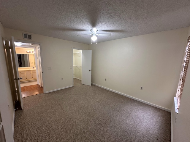 1401 Village Blvd Unit 1914, West Palm Beach, FL 33409 - unfurnished bedroom with carpet floors, a walk in closet, a ceiling fan, and a textured ceiling
