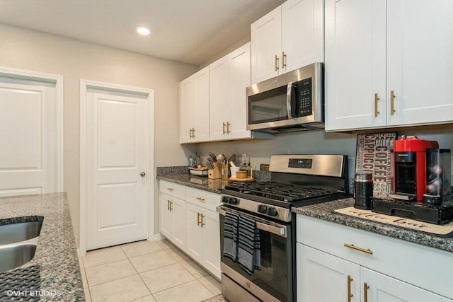 5126 Dandelion St, Apollo Beach, FL 33572 - kitchen featuring stainless steel appliances, white cabinets, light tile patterned floors, dark stone counters, and recessed lighting