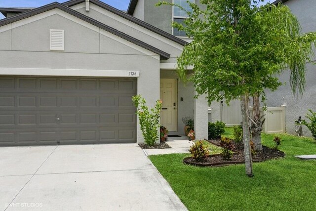 5126 Dandelion St, Apollo Beach, FL 33572 - view of front of house with driveway, stucco siding, a front yard, and an attached garage