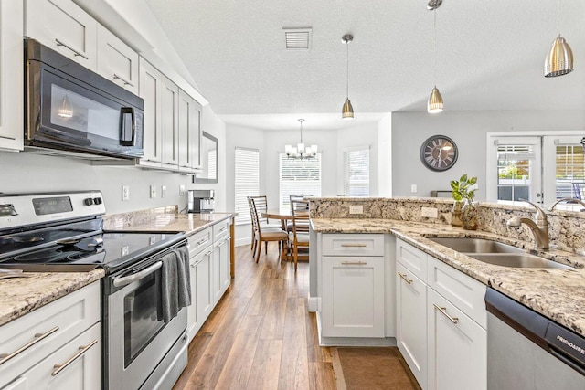 5533 NW Cordrey St, Port Saint Lucie, FL 34986 - kitchen with appliances with stainless steel finishes, hardwood / wood-style floors, a chandelier, hanging light fixtures, and a textured ceiling