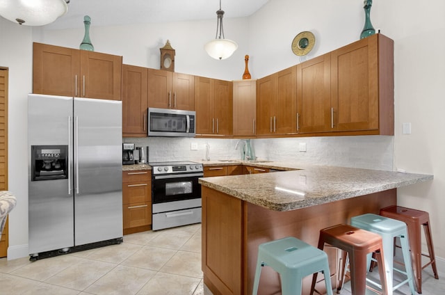 9927 Boca Gardens Trl Unit A, Boca Raton, FL 33496 - kitchen with appliances with stainless steel finishes, a peninsula, decorative backsplash, brown cabinets, and high vaulted ceiling