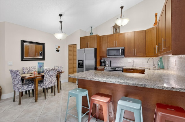 9927 Boca Gardens Trl Unit A, Boca Raton, FL 33496 - kitchen with stainless steel appliances, decorative backsplash, brown cabinetry, a peninsula, and decorative light fixtures