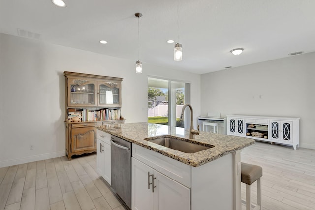 774 SE Ablett Ln, Port Saint Lucie, FL 34984 - kitchen with dishwasher, light wood-type flooring, an island with sink, light stone countertops, and recessed lighting