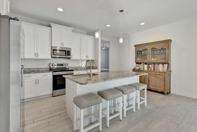 774 SE Ablett Ln, Port Saint Lucie, FL 34984 - kitchen featuring stainless steel appliances, tasteful backsplash, light wood finished floors, light stone counters, and recessed lighting