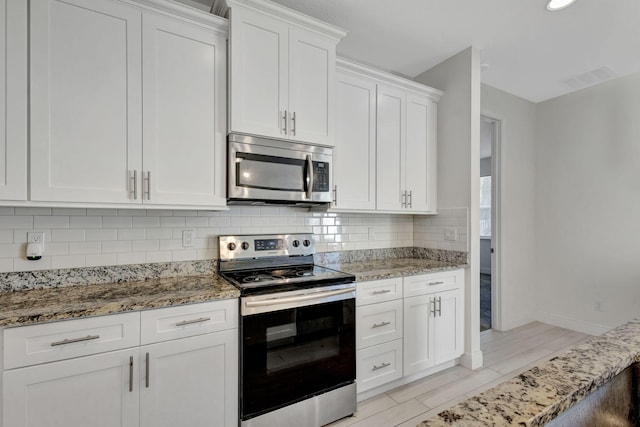 774 SE Ablett Ln, Port Saint Lucie, FL 34984 - kitchen featuring appliances with stainless steel finishes, backsplash, light stone countertops, and white cabinets