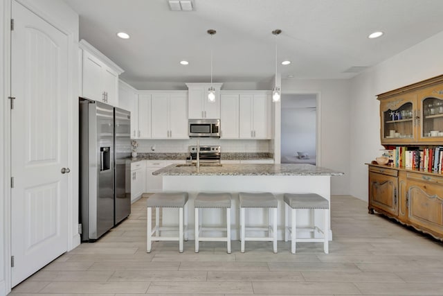 774 SE Ablett Ln, Port Saint Lucie, FL 34984 - kitchen featuring appliances with stainless steel finishes, light wood-style floors, backsplash, light stone countertops, and recessed lighting