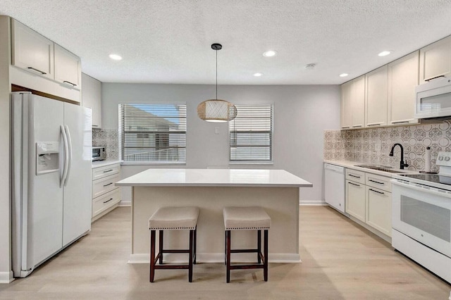74 Normandy Unit B, Delray Beach, FL 33484 - kitchen featuring white appliances, tasteful backsplash, a kitchen island, light wood-style flooring, and recessed lighting