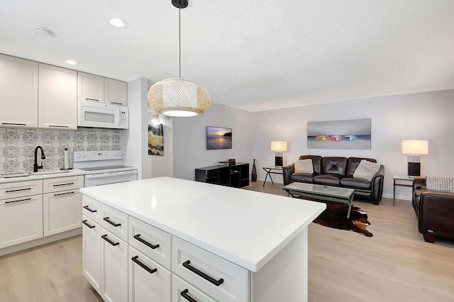 74 Normandy Unit B, Delray Beach, FL 33484 - kitchen with white appliances, light wood-style flooring, backsplash, light countertops, and pendant lighting