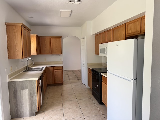 1965 SW Bellevue Ave, Port Saint Lucie, FL 34953 - kitchen with white appliances, arched walkways, light tile patterned floors, light countertops, and brown cabinetry