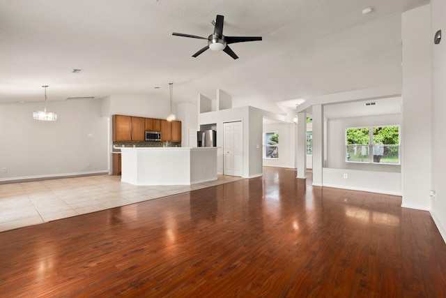 1901 SW Diamond St, Port Saint Lucie, FL 34953 - unfurnished living room with ceiling fan, vaulted ceiling, a chandelier, and light wood-style flooring